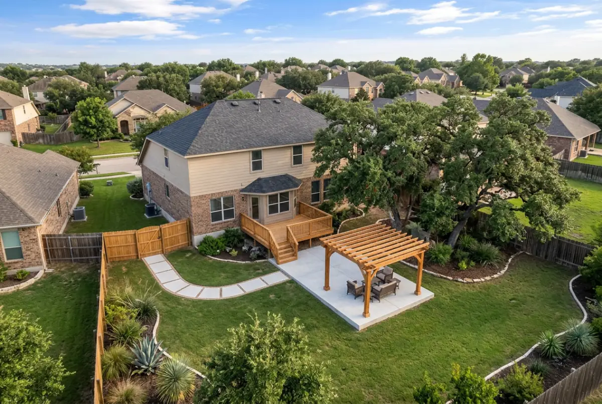 Aerial view of a back yard with a concrete patio, a shade pergola and a curved path